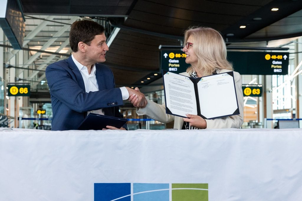 Premierminister David Eby und YVR-CEO Tamara Vrooman schütteln sich die Hände.