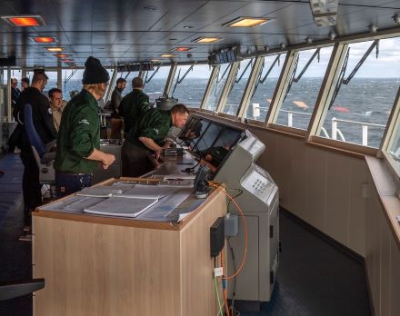 Arbeiter in einem Schiff vor einem Navigationssystem
